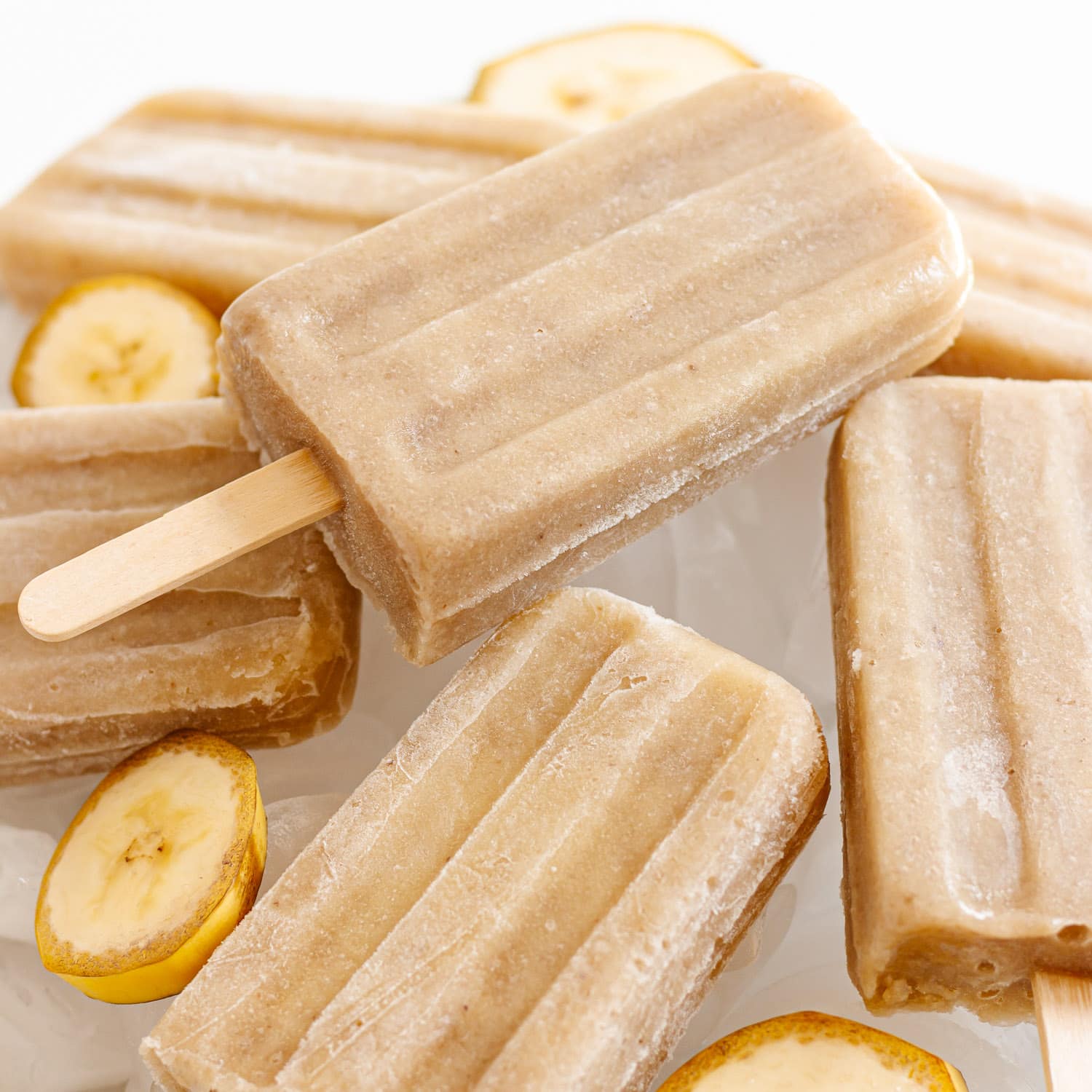 Pile of banana popsicles sitting on ice.
