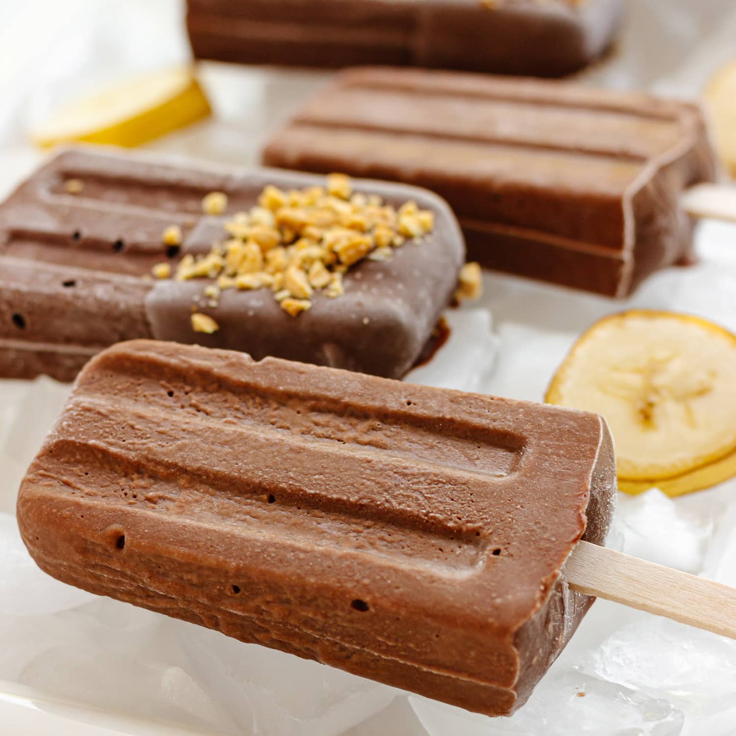 Chocolate banana popsicles sitting on ice.