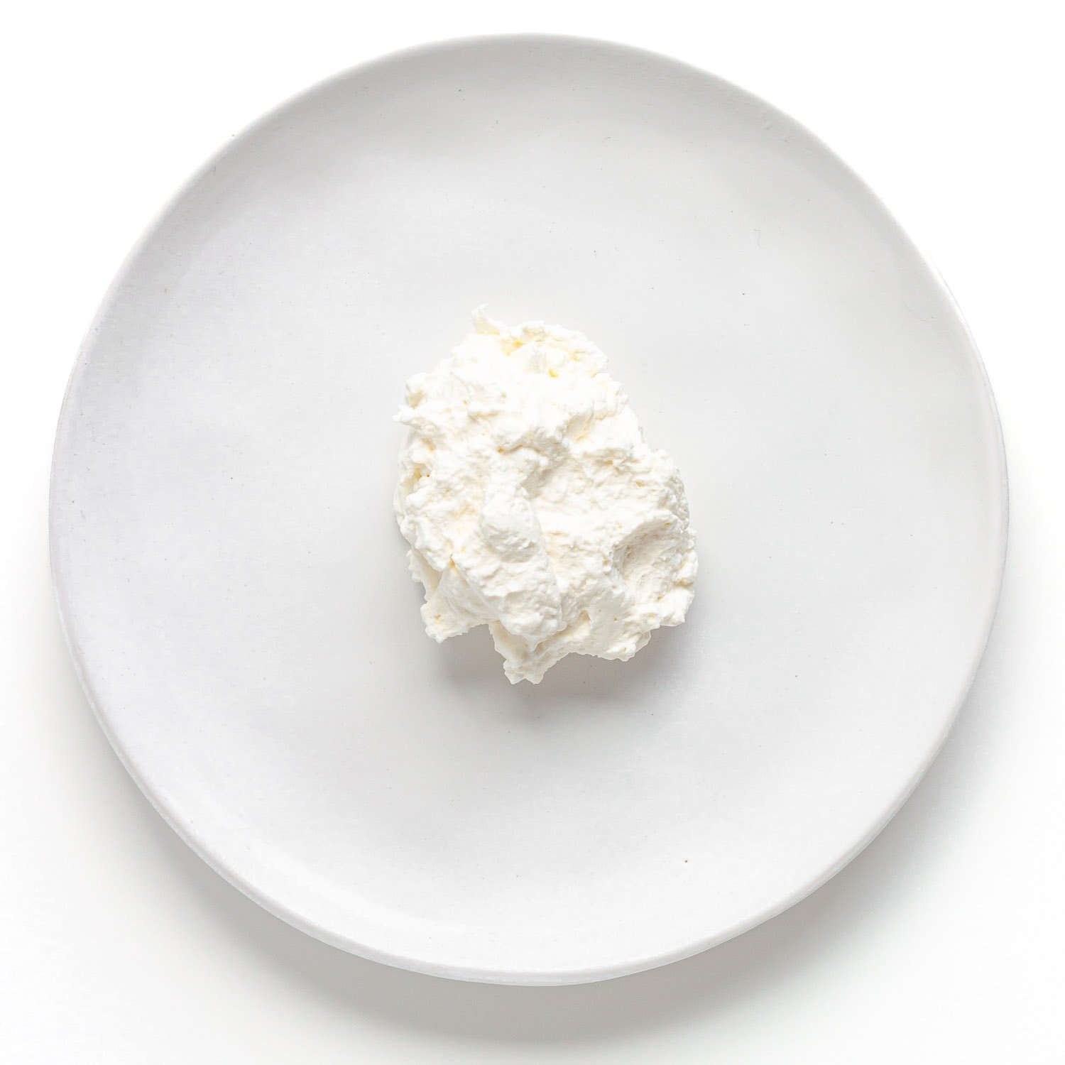Dollop of whipped cream on the center of a white plate.