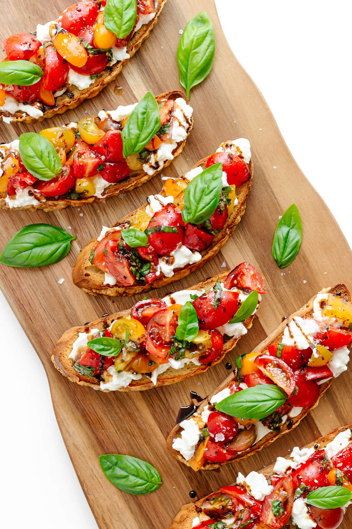 Burrata tomato bruschetta on a wooden serving boad.