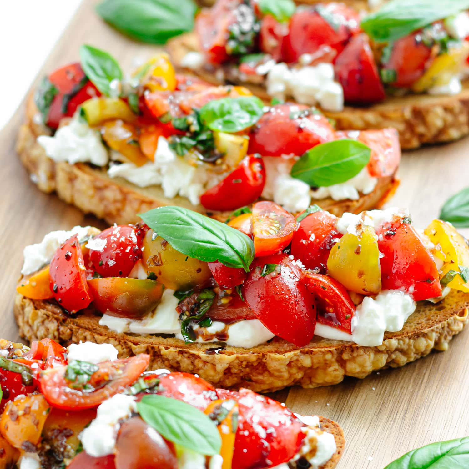 Tomato basil burrata bruschetta on a wooden board.