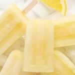Closeup of a pile of lemon popsicles with text overlay that reads "Refreshing Lemon Popsicles".