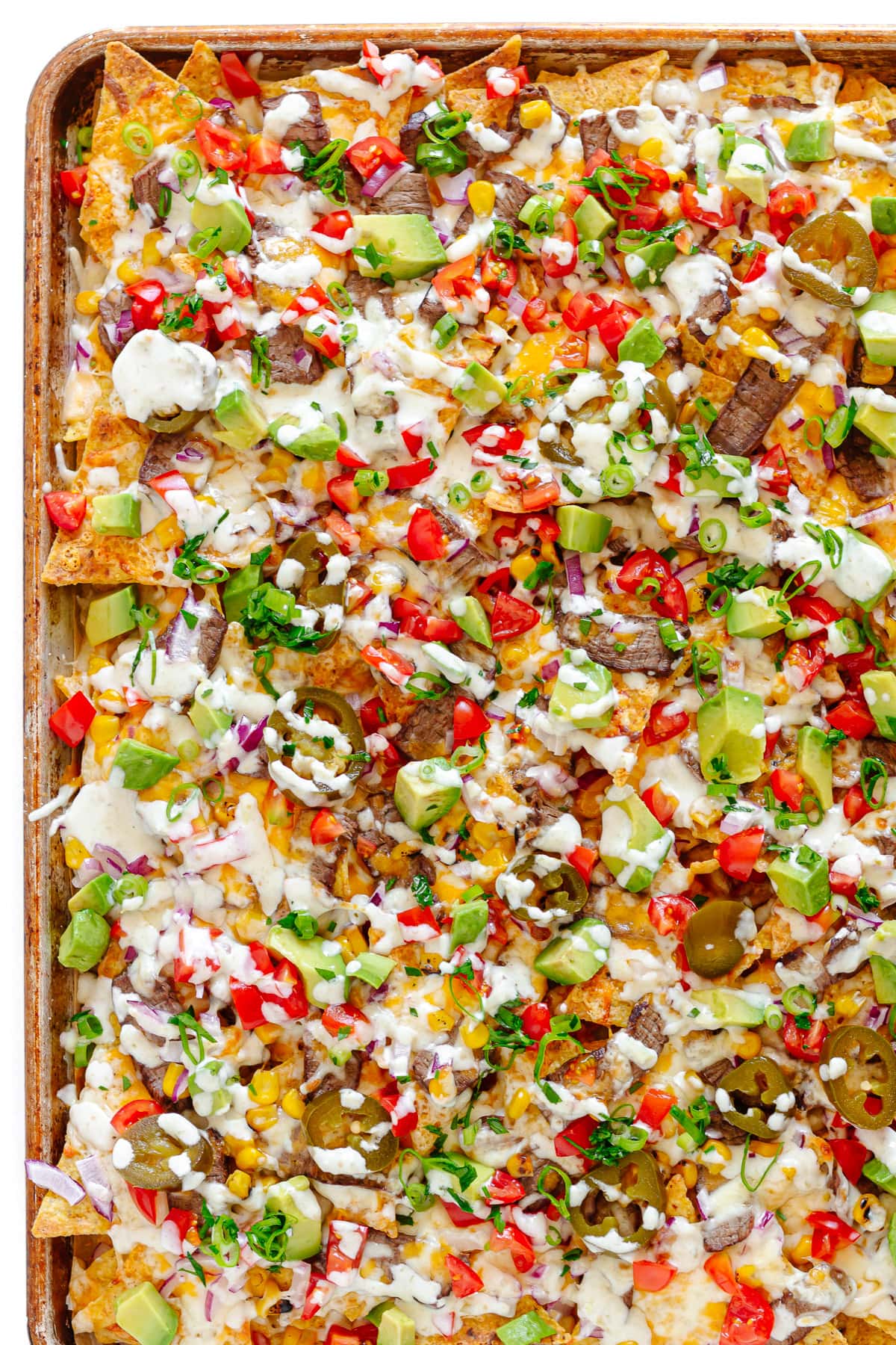 Closeup of leftover steak nachos on a sheet pan.