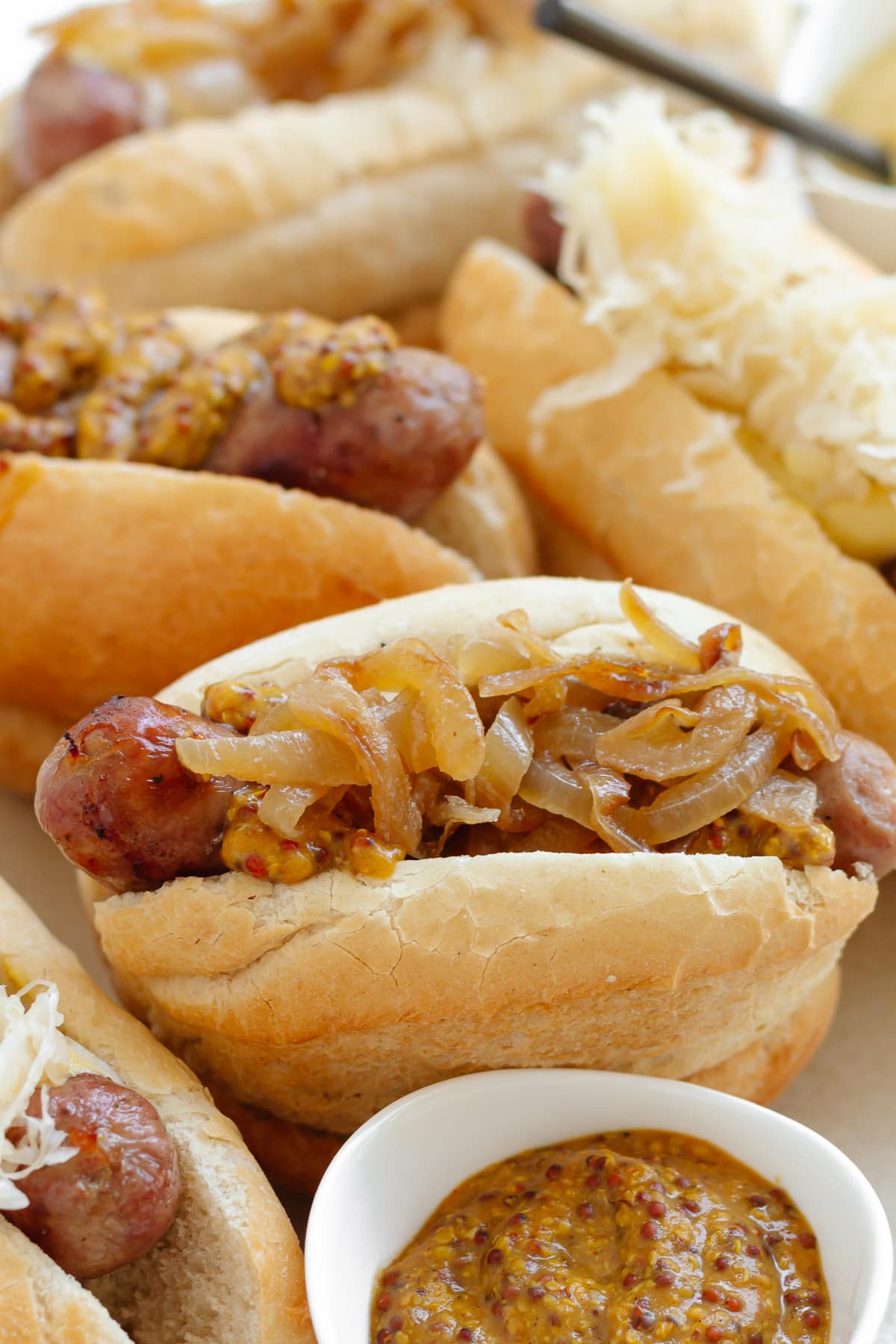 Grilled brats on buns with various toppings like mustard, beer braised onions and sauerkraut.