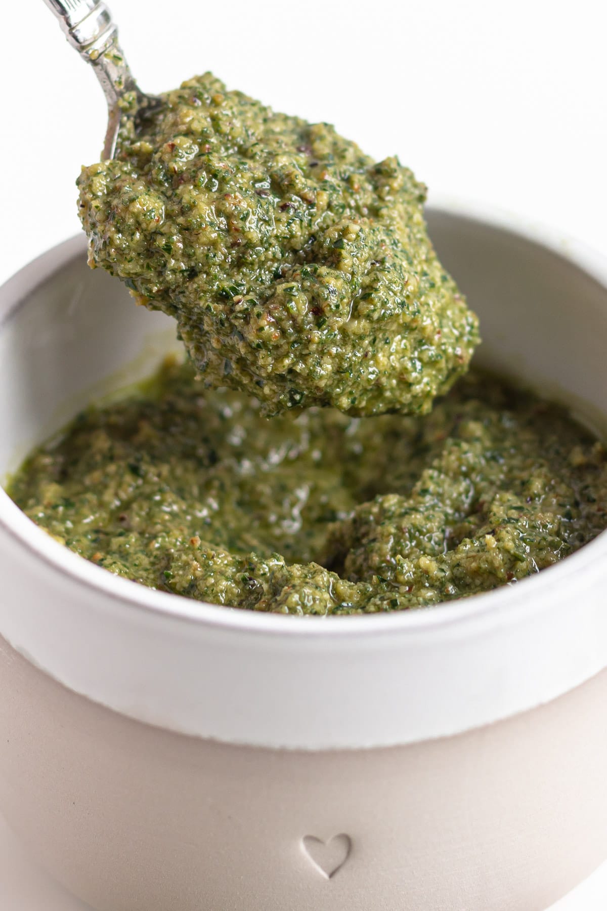 Small bowl of homemade sage pesto with spoon lifting some out.