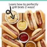 Wooden board with brats on buns and a variety of toppings with text overlay that reads "How To Cook Brats On The Grill".