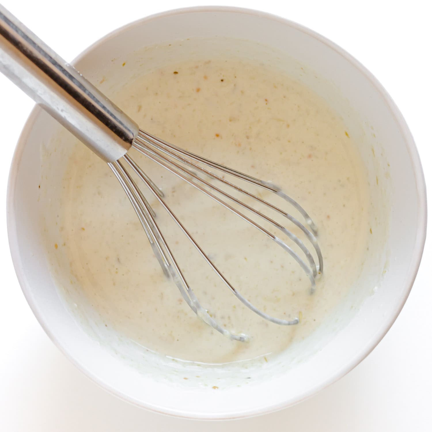 Whisking together easy salsa verde crema in a white bowl.