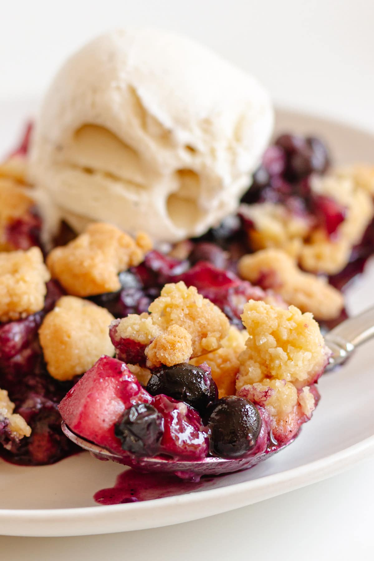 Spoonful of blueberry apple crumble dessert.