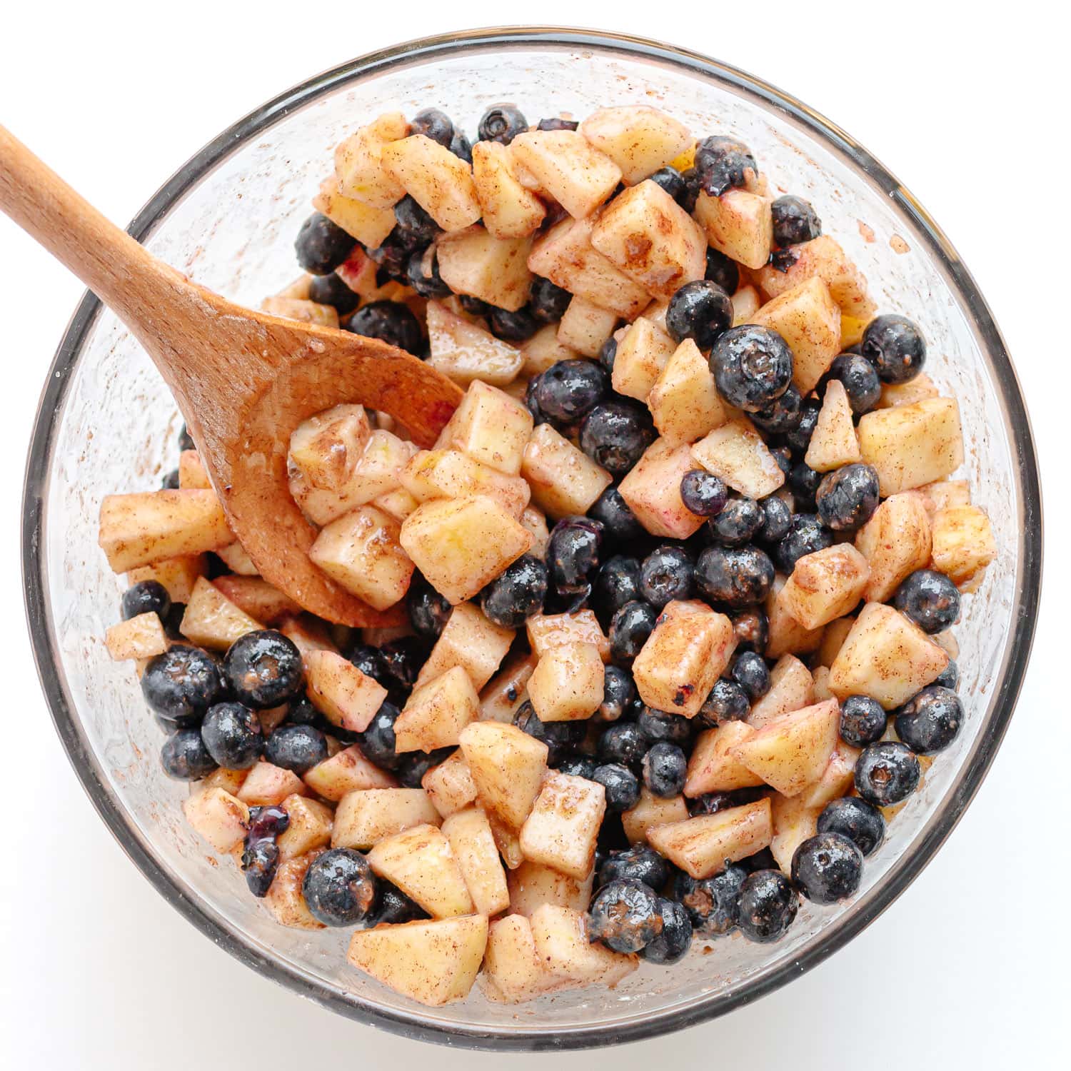 Glass bowl of blueberry and apple crumble fruit mixture.