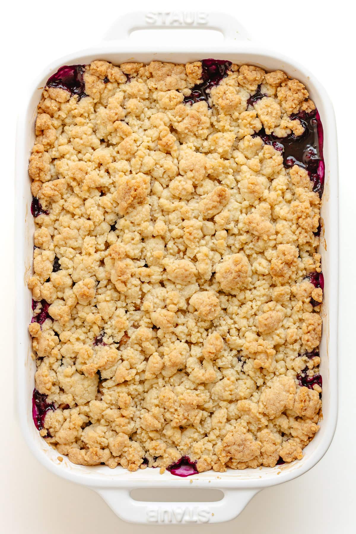 Finished baked blueberry apple crumble in white baking dish.
