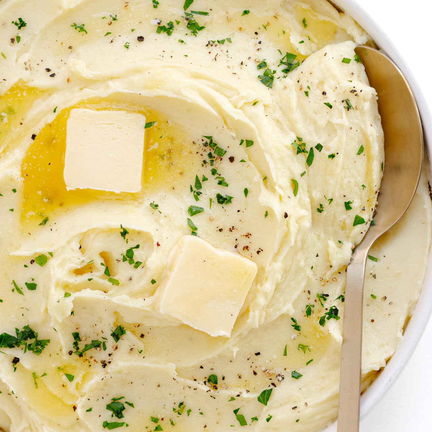 Closeup of creamy mashed potatoes in a bowl with serving spoon.