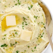 Creamy whipped mashed potatoes in a serving bowl with serving spoon.