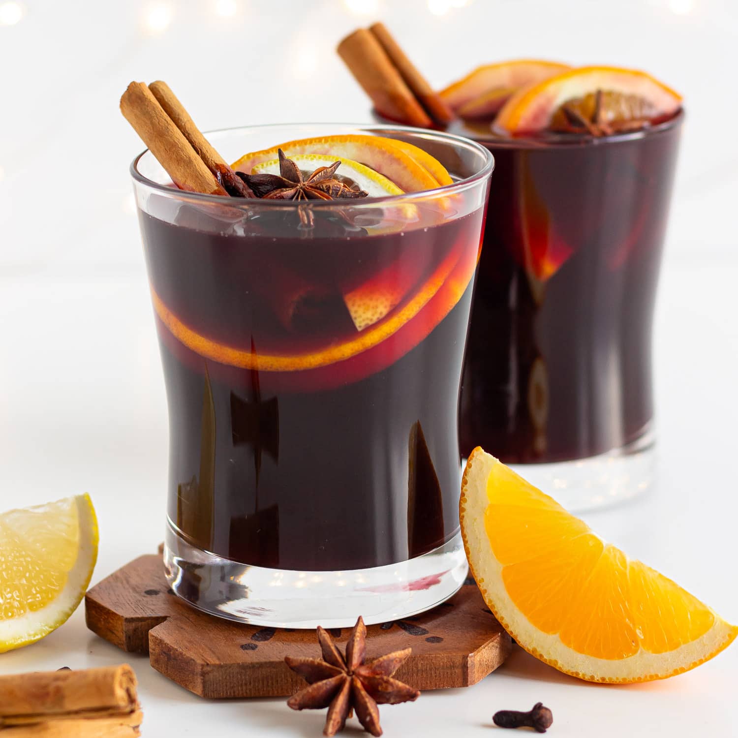 Two glasses of Gluhwein garnished with orange, cinnamon sticks and star anise.