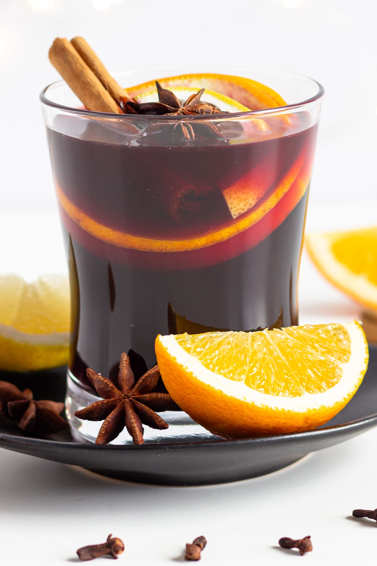 Glass of homemade German mulled wine garnished with orange, lemon, cinnamon sticks, star anise and cloves.