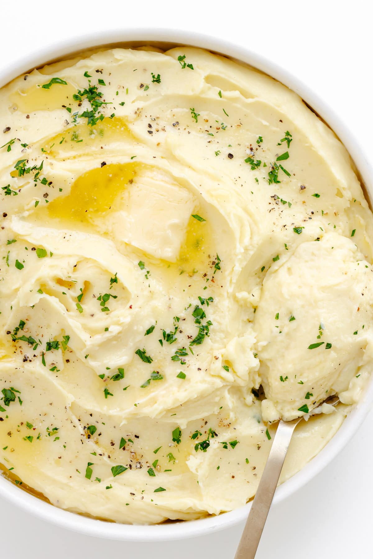 Serving bowl of mashed potatoes with a serving spoon.