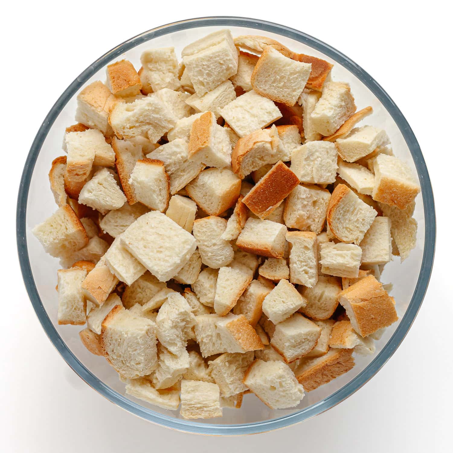 Cubed bread in a glass mixing bowl.