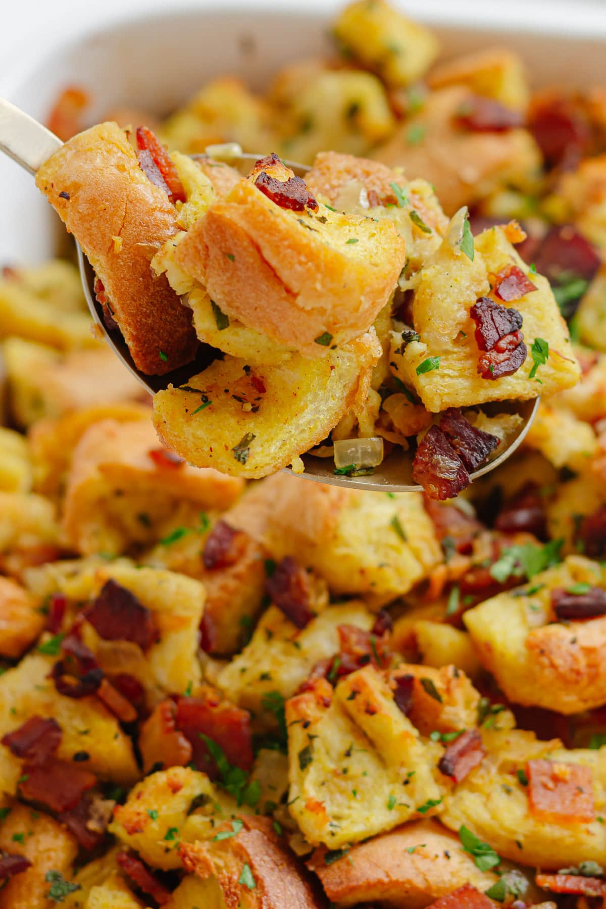 Spoonful of stuffing being lifted from serving dish.