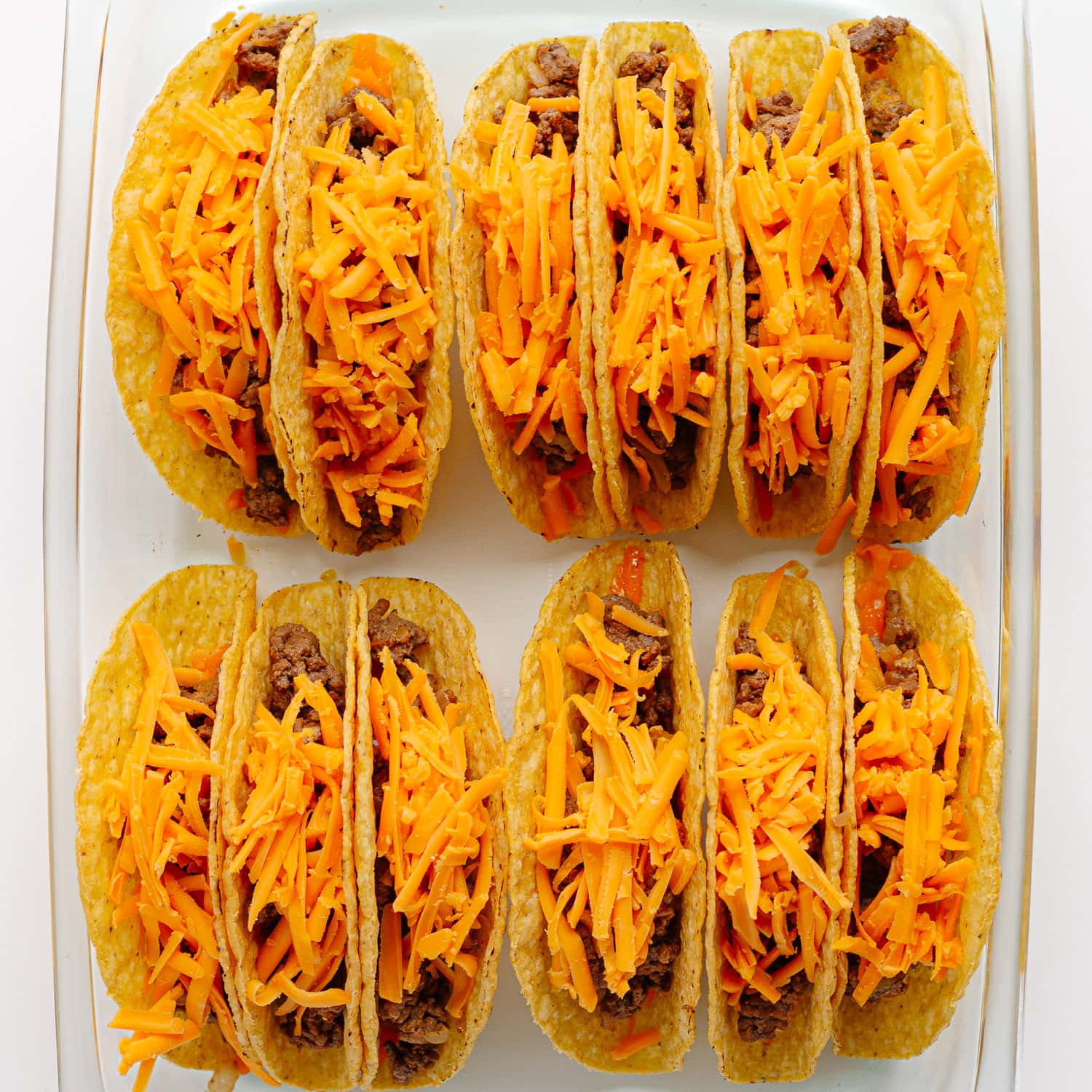Assembled cheeseburger tacos in a baking dish ready to be baked.