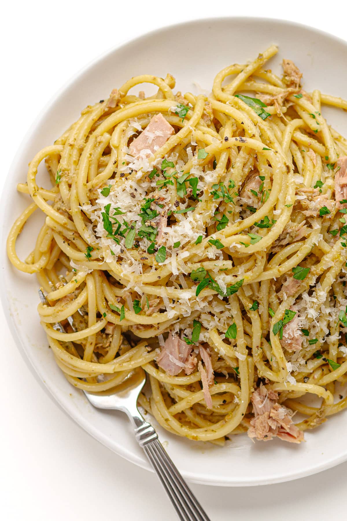 Tuna pasta with pesto on a white plate with fork.