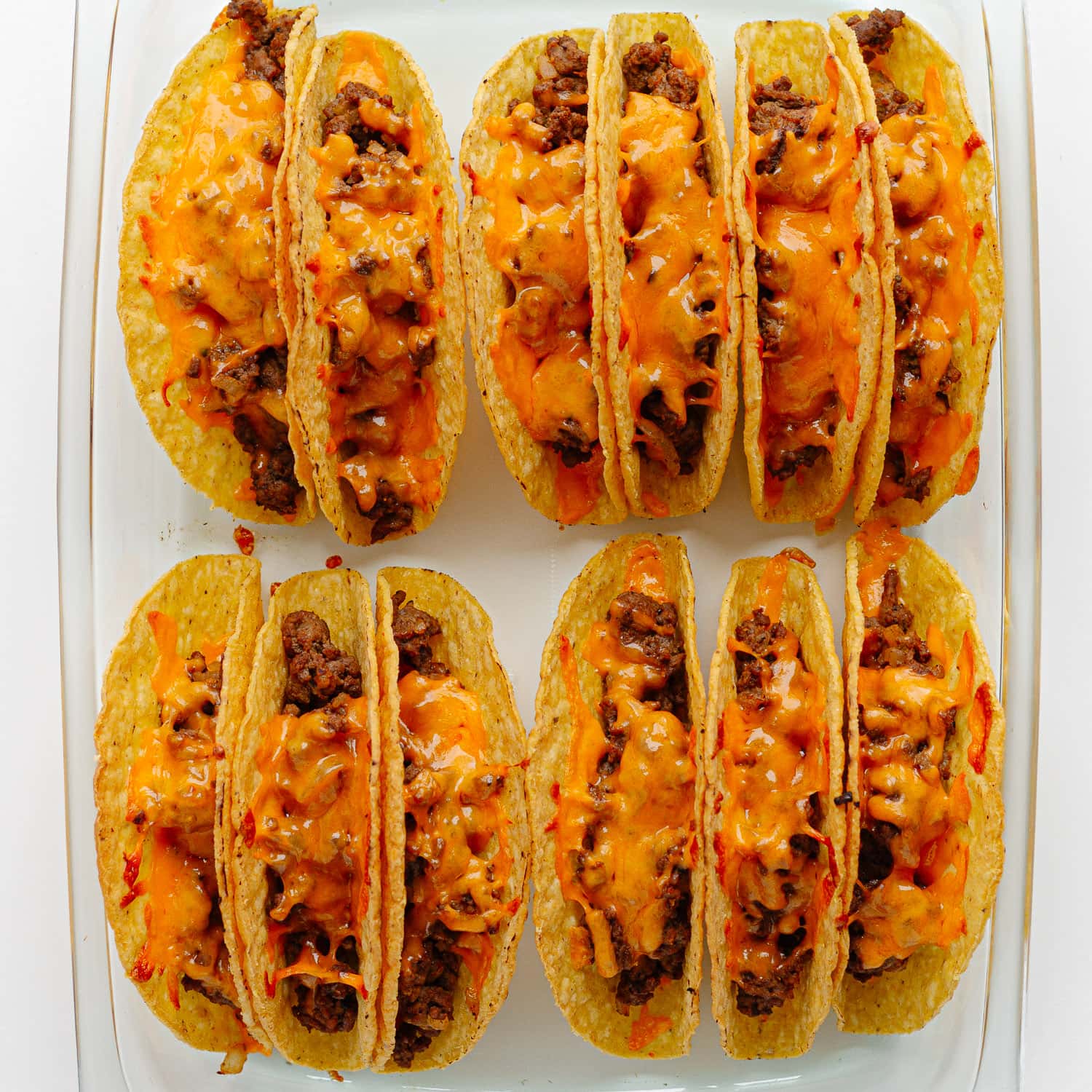 Glass casserole dish of cheeseburger tacos after baking and ready for toppings.