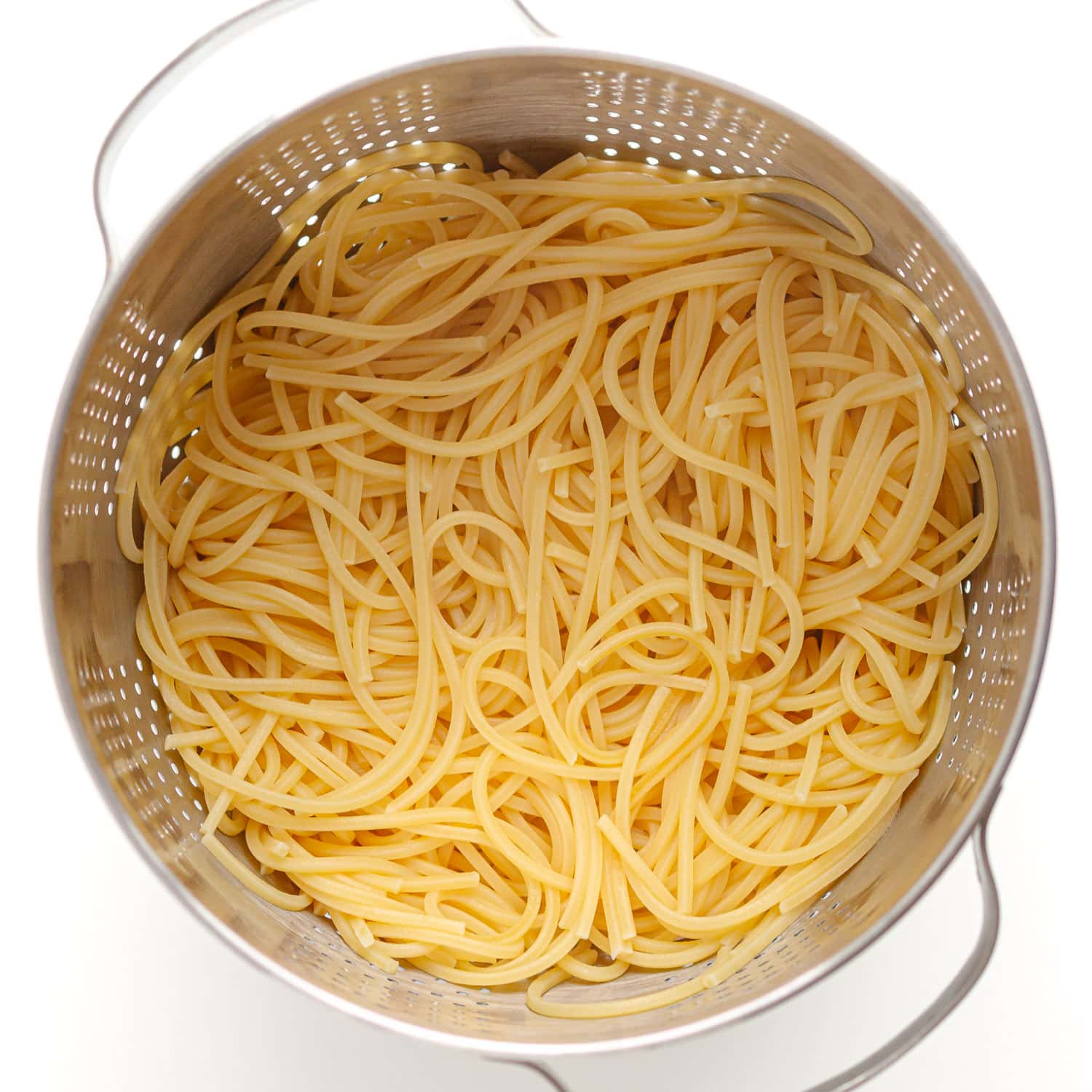 Cooked spaghetti in a stainless steel strainer.