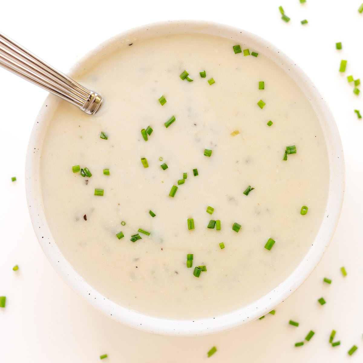 Bowl of creamy gorgonzola sauce garnished with chopped chives.