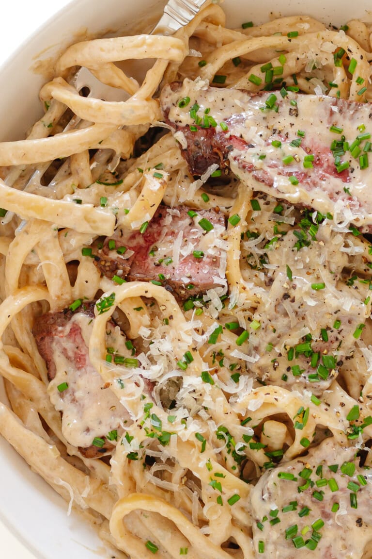 Closeup of creamy steak pasta with a fork.