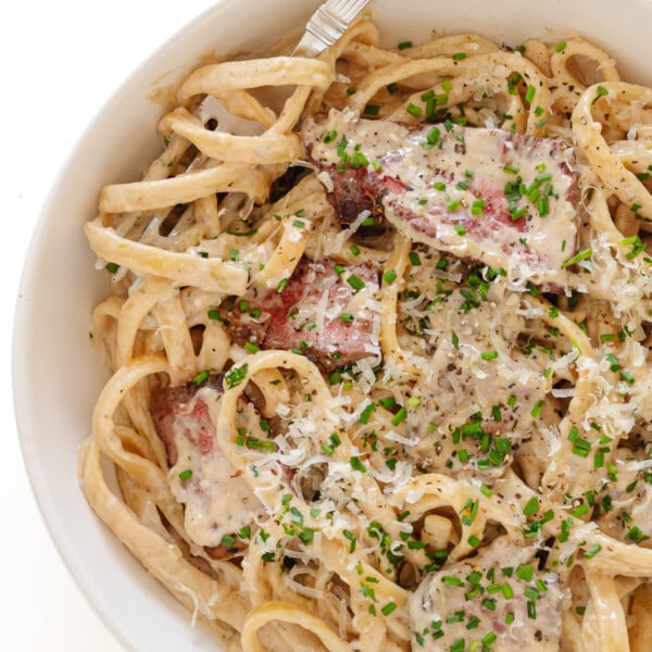 Creamy steak pasta with gorgonzola sauce on a white plate with fork.