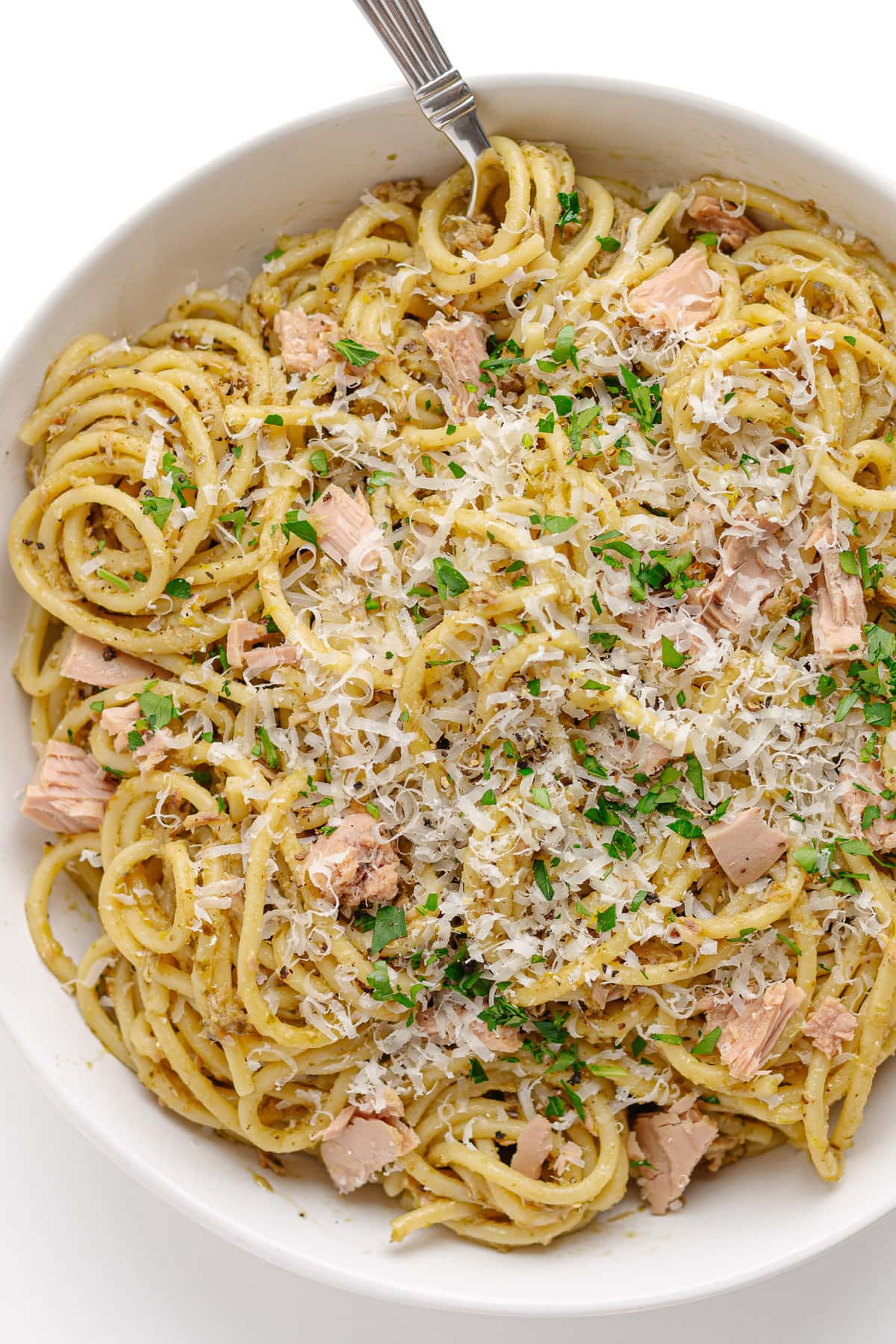 White bowl of tuna pesto spaghetti with fork.