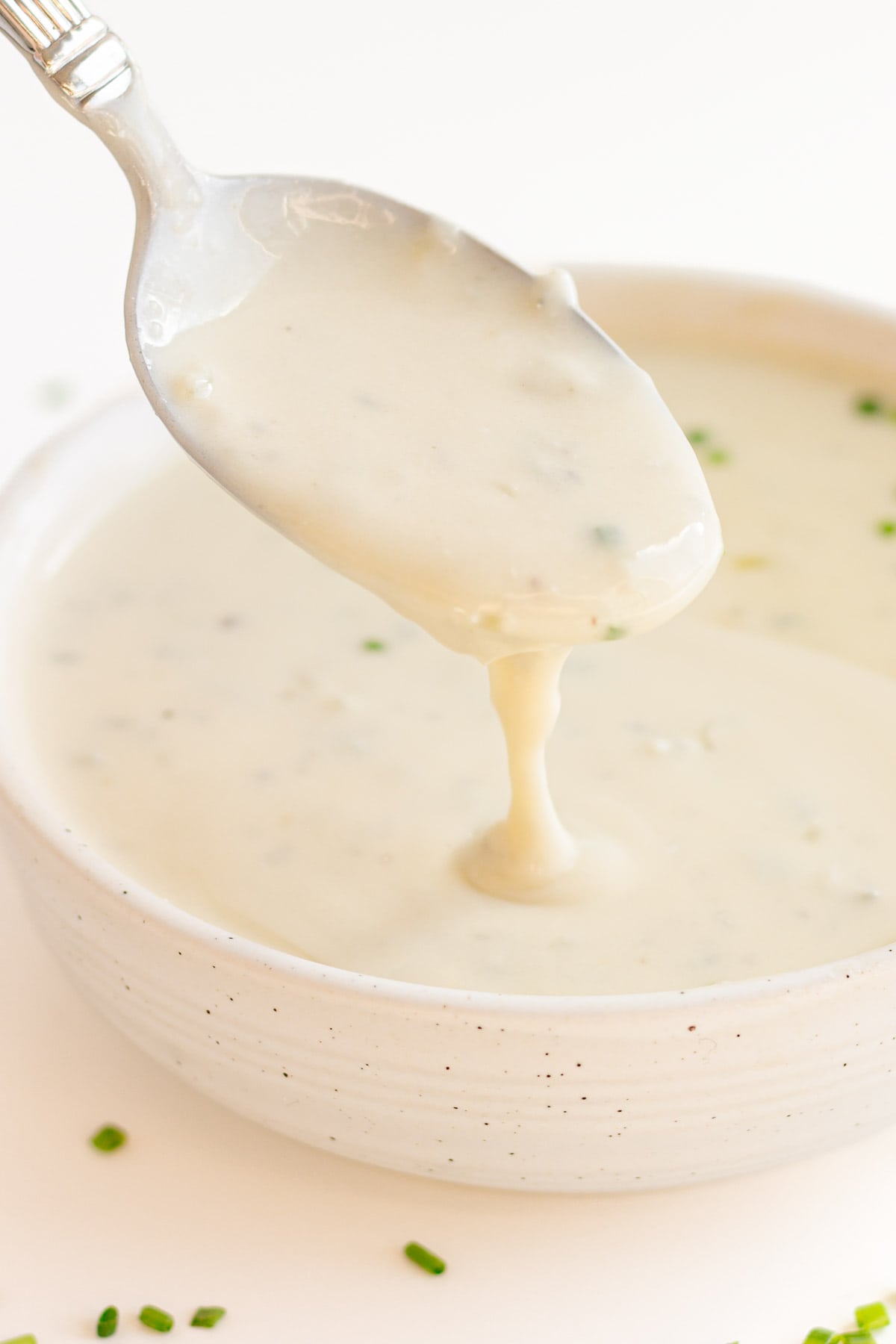 Gorgonzola sauce dripping off a spoon into a small bowl.