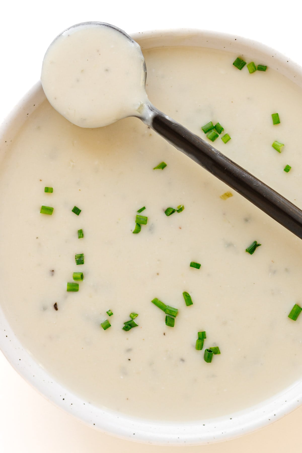 Bowl of gorgonzola sauce with a black spoon balanced across the top.