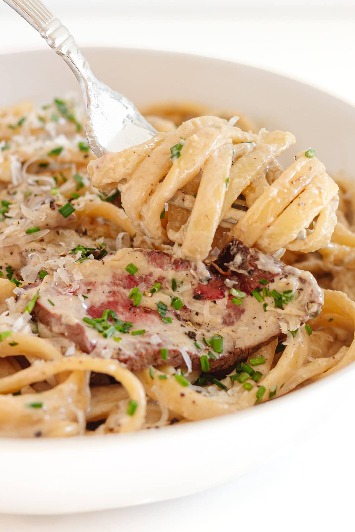 Fork lifting up some steak gorgonzola pasta.