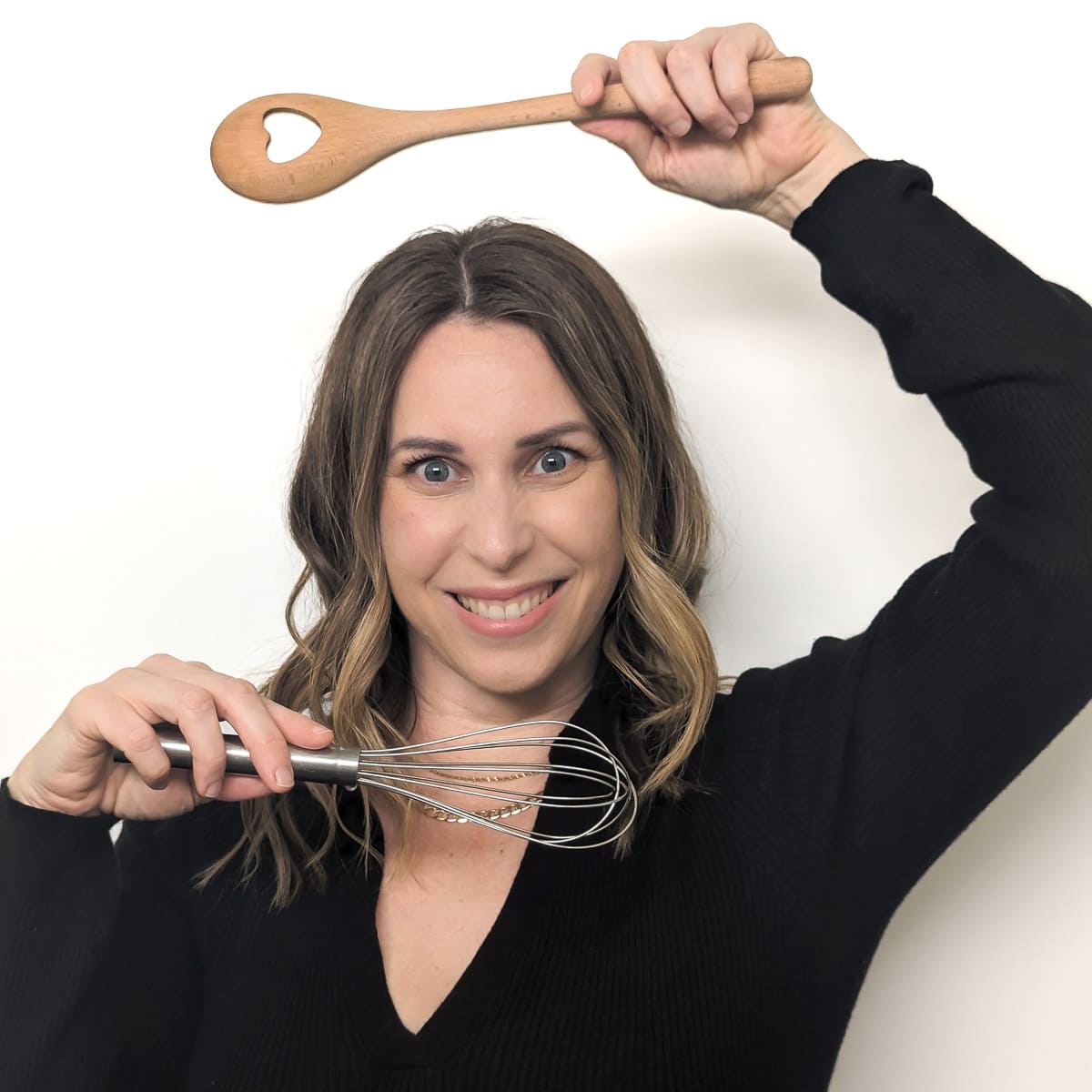 Vanessa Gilic headshot holding a wooden spoon and whisk.