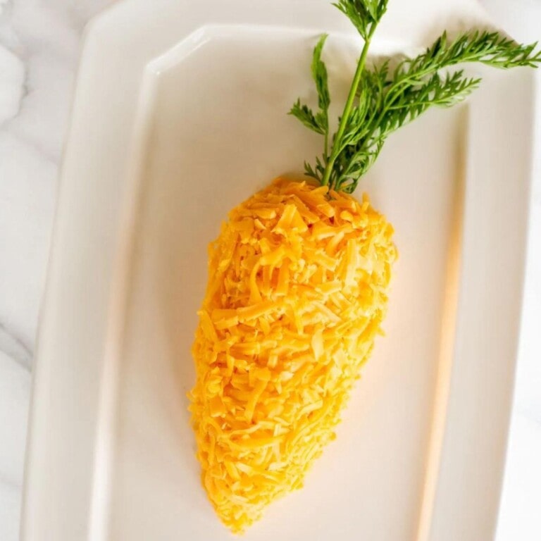 Carrot shaped cheeseball on a white platter.