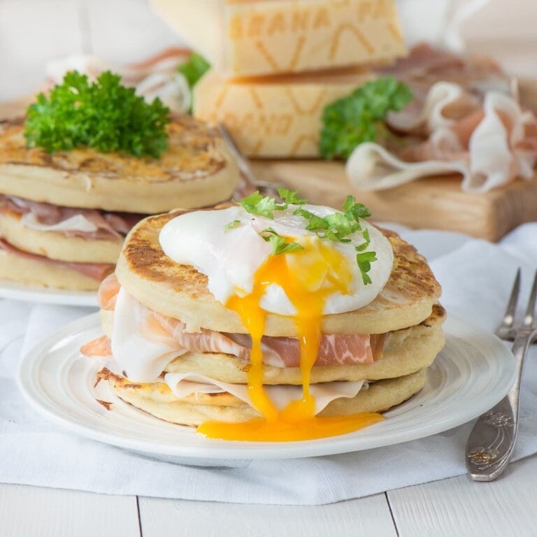 Stack of grana padano pancakes topped with a poached egg.