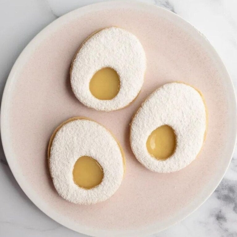Three lemon ginger easter egg cookies on a pale pink serving plate.