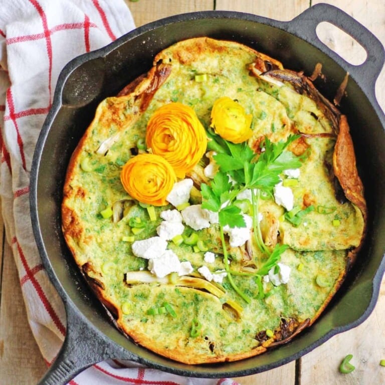 Savory dutch baby with spring onions and goat cheese in a cast iron skillet.