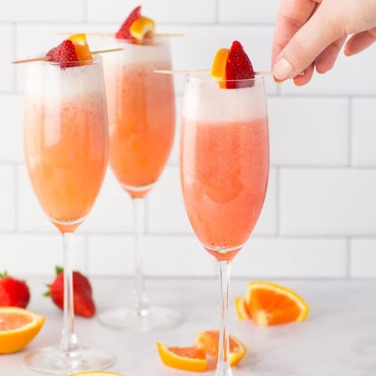 Three glasses of strawberry orange mimosas.