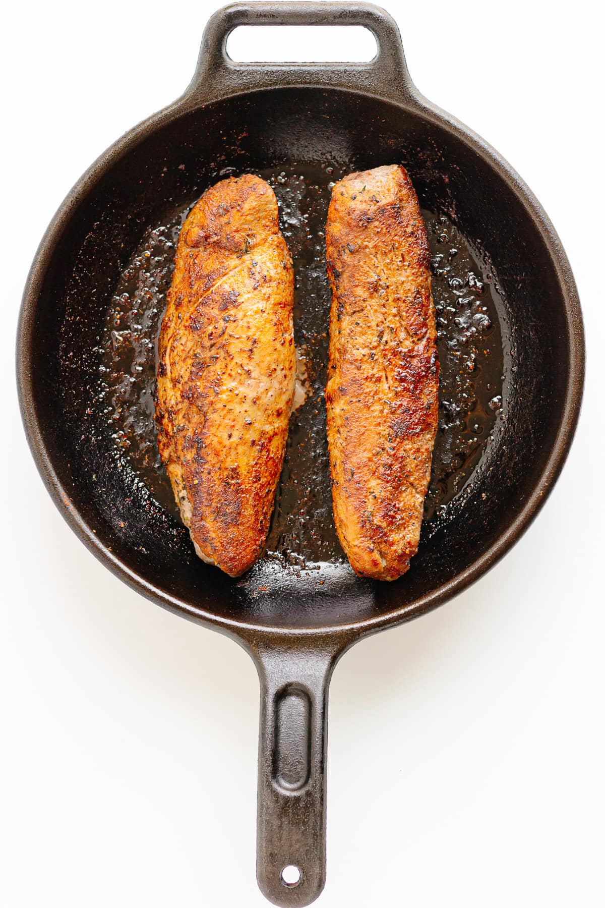 Two pork tenderloin in a cast iron skillet.