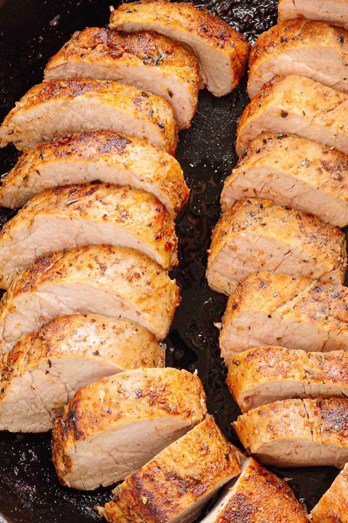 Sliced pork tenderloin in a cast iron skillet.