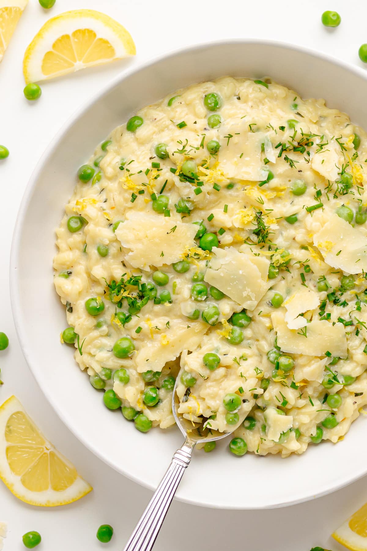 Lemon and pea risotto in a white bowl with spoon.