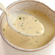 Spoon lifting Creamy Dijon Sauce out of a sauce jug.