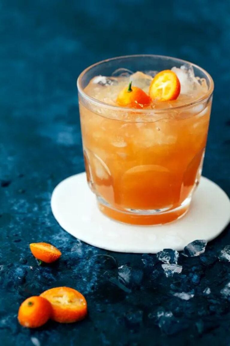 Glass of earl grey mocktail garnished with kumquats.