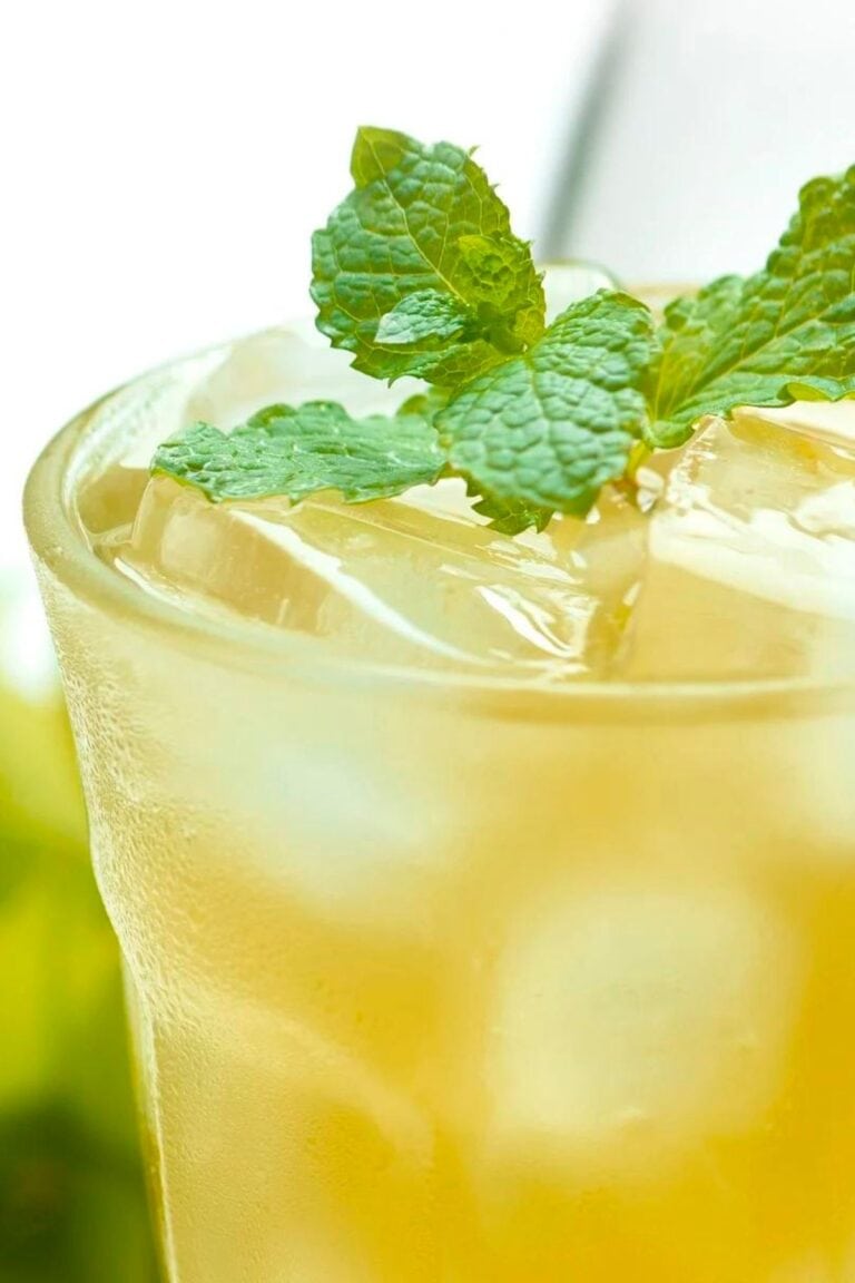 Closeup of a glass of honey ginger limeade garnished with a sprig of fresh mint.