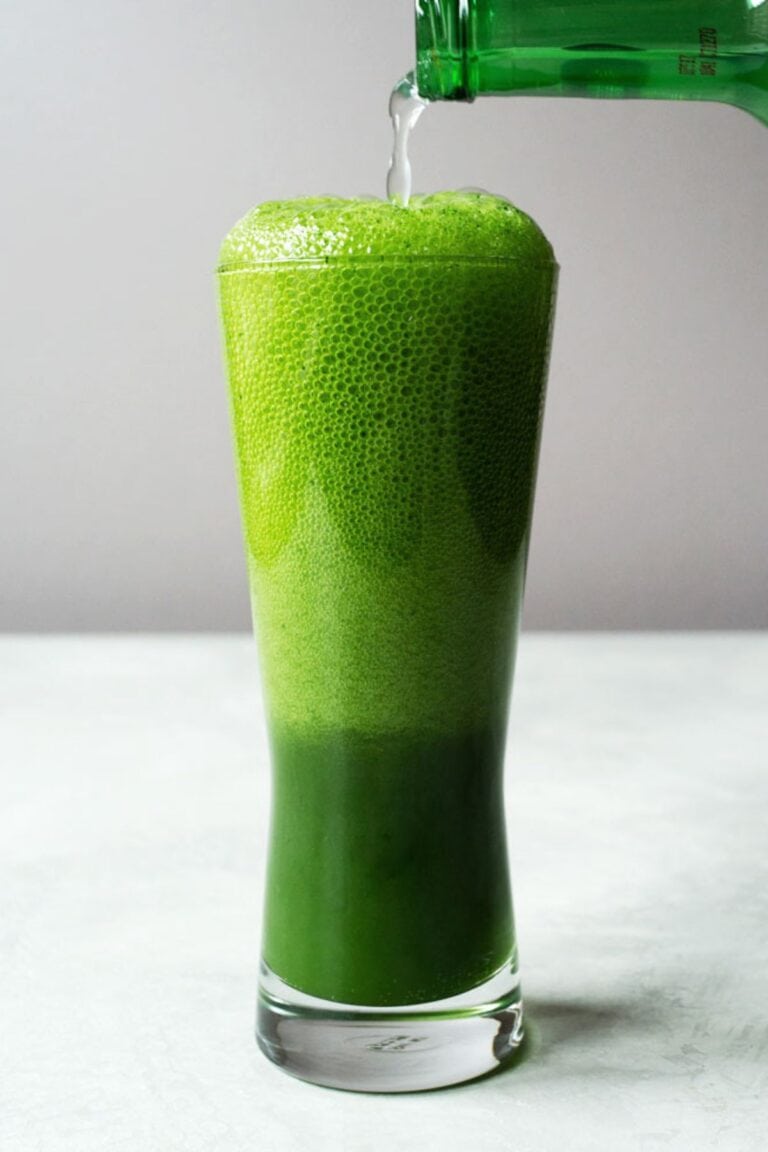 Ginger beer being poured into a tall glass of matcha ginger beer drink.