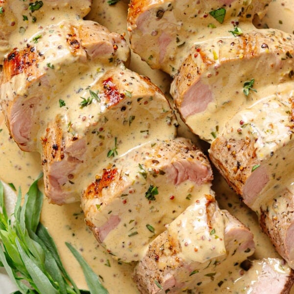 Sliced pork tenderloin with mustard sauce and fresh tarragon.