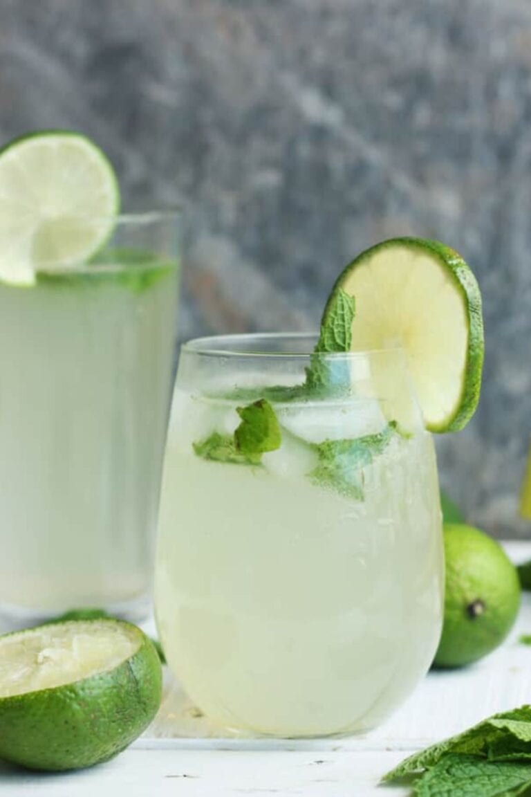 Two glasses of virgin mojitos garnished with lime and mint.