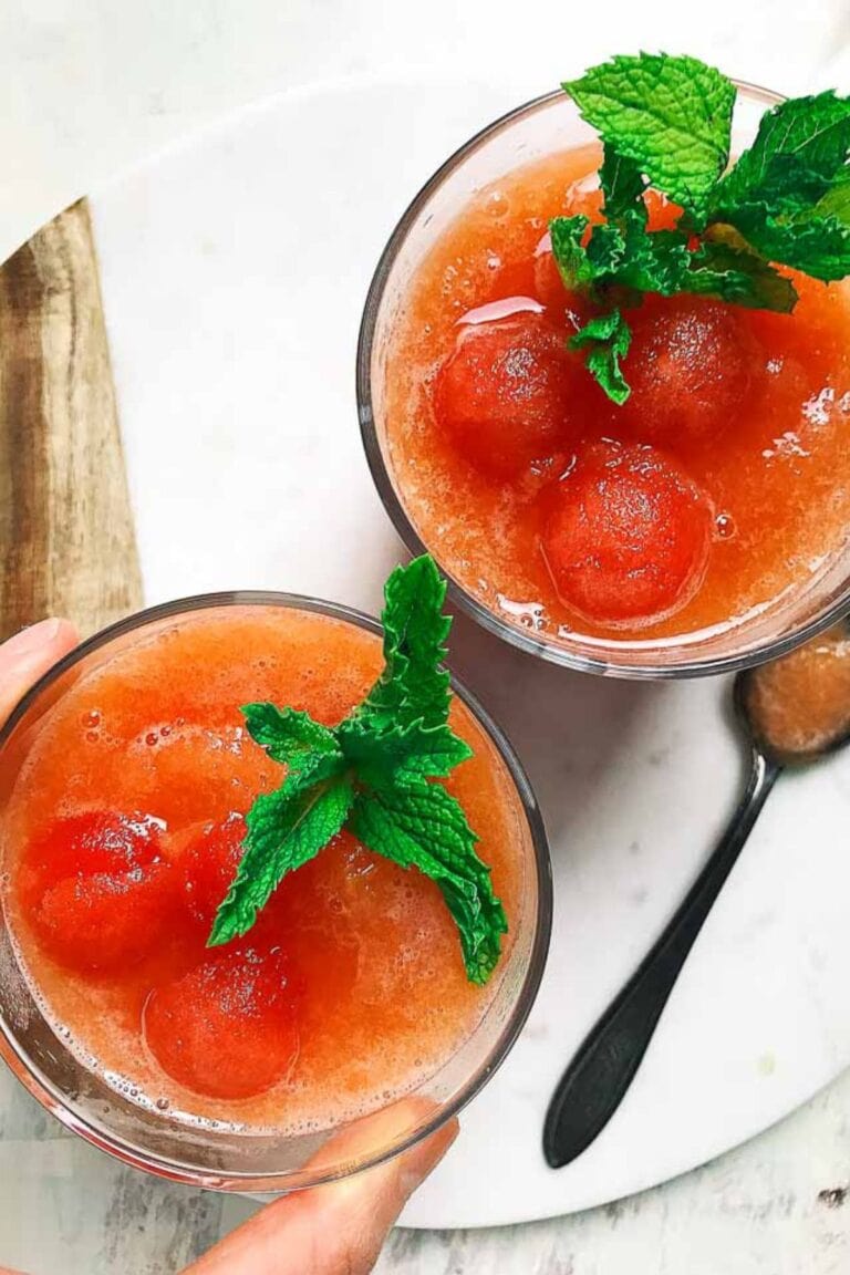 Overhead of two glasses of watermelon peach mocktail garnished with fresh mint.