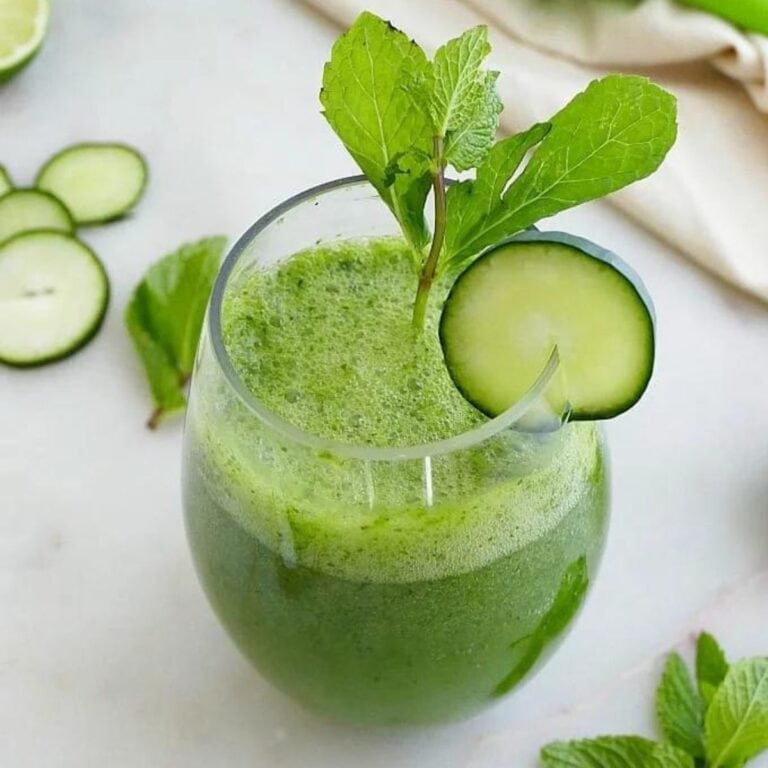 Glass of blended cucumber gin cocktail garnished with sprig of mint and cucumber slice.