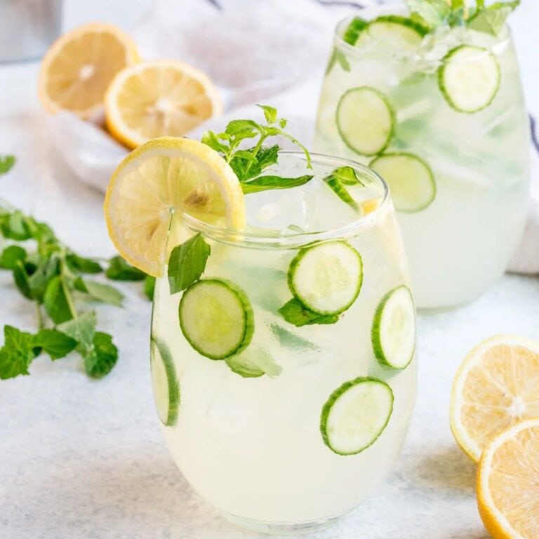 Two glasses of cucumber lemonade vodka cocktail garnished with cucumber and lemon slices.